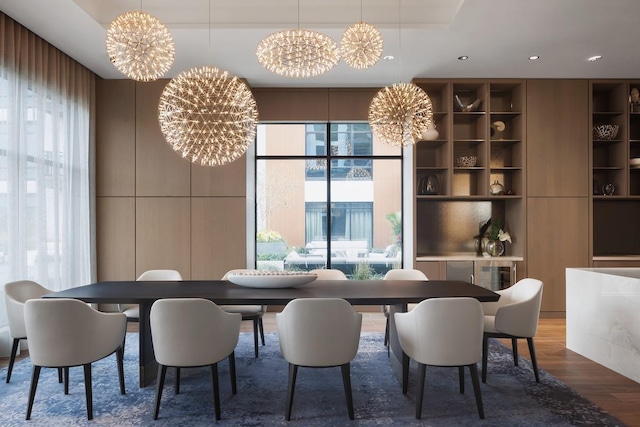 dining room featuring built in shelves, a tray ceiling, wood finished floors, recessed lighting, and a chandelier