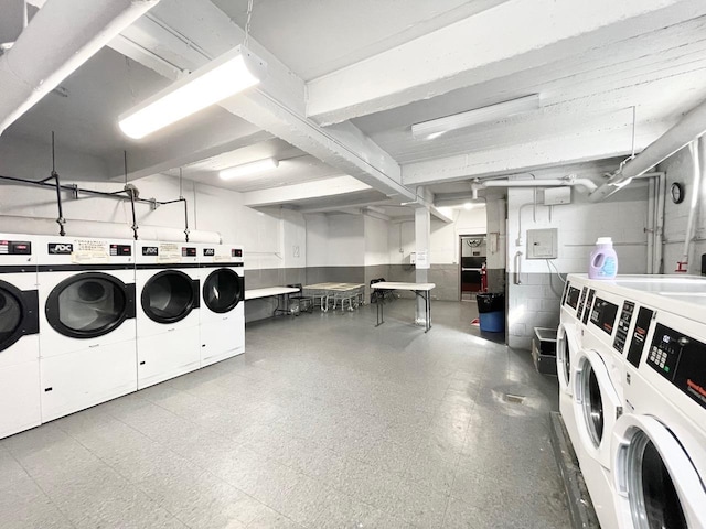 community laundry room with tile patterned floors, concrete block wall, and separate washer and dryer