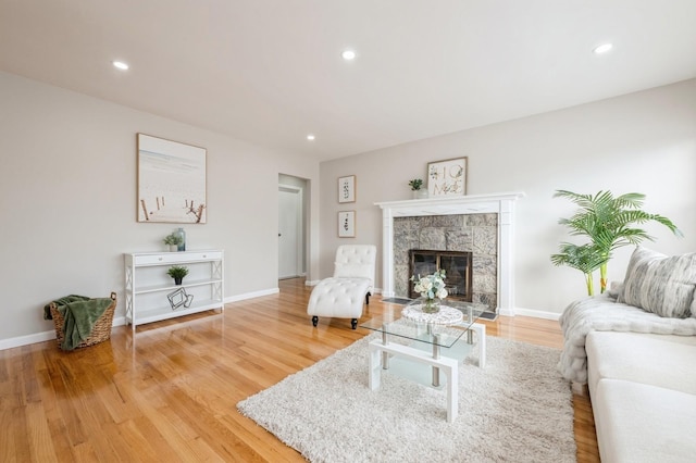 living room with recessed lighting, a tile fireplace, light wood-type flooring, and baseboards