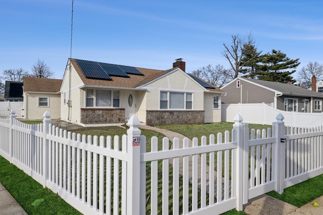 view of front facade featuring stucco siding, a fenced front yard, stone siding, roof mounted solar panels, and a chimney