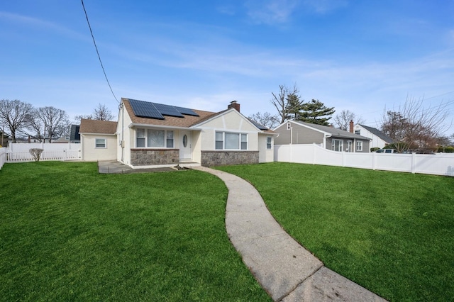 view of front facade featuring stucco siding, a front lawn, stone siding, a fenced backyard, and solar panels