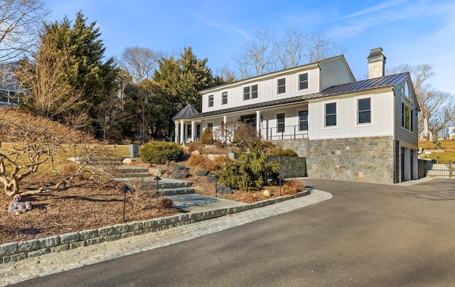 view of front of property with aphalt driveway, stone siding, metal roof, and a standing seam roof