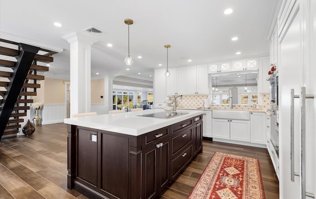 kitchen with a sink, white cabinetry, decorative columns, black electric stovetop, and dark brown cabinets