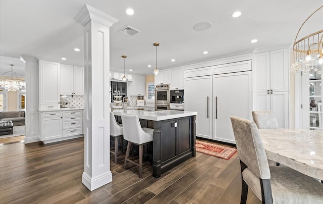 kitchen featuring visible vents, white cabinets, an inviting chandelier, and decorative columns