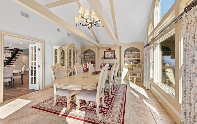 dining space featuring visible vents, built in shelves, stairs, french doors, and an inviting chandelier