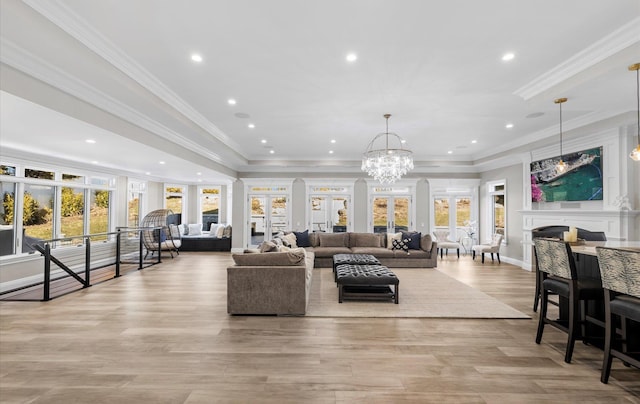 living area featuring crown molding, a fireplace, light wood-style floors, and a healthy amount of sunlight