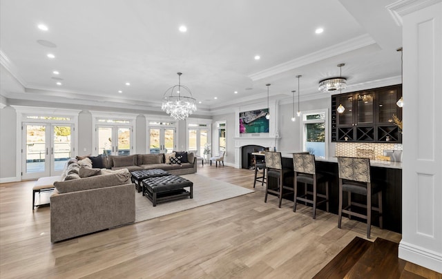 living room with bar area, plenty of natural light, french doors, and light wood finished floors