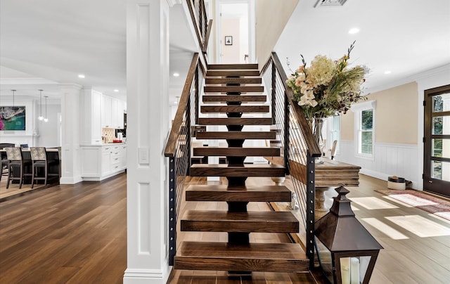 stairway featuring wood finished floors, visible vents, recessed lighting, wainscoting, and crown molding