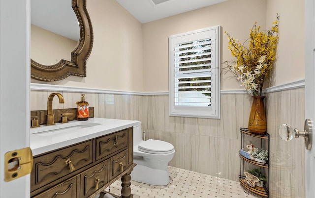 bathroom featuring a wainscoted wall, toilet, and vanity