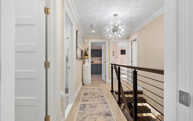 hall featuring baseboards, an inviting chandelier, ornamental molding, an upstairs landing, and light wood-type flooring