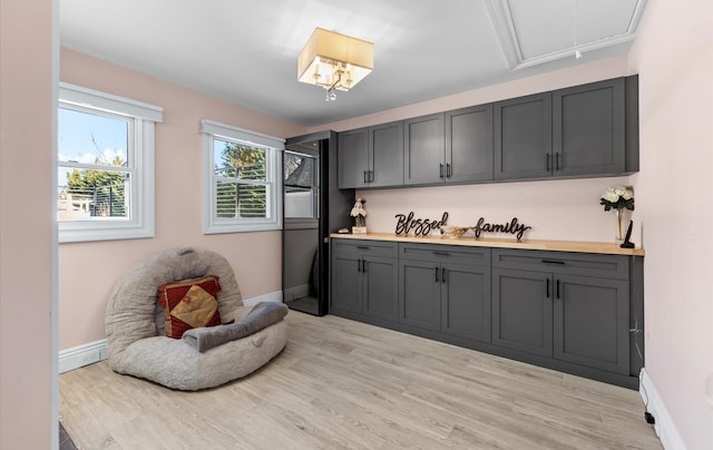 interior space with light countertops, light wood-style flooring, gray cabinets, and baseboards