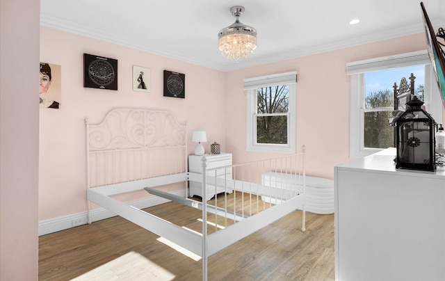 bedroom featuring a notable chandelier, ornamental molding, baseboards, and wood finished floors