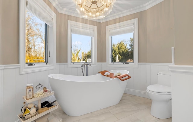 full bathroom with a chandelier, a wainscoted wall, toilet, and a freestanding tub