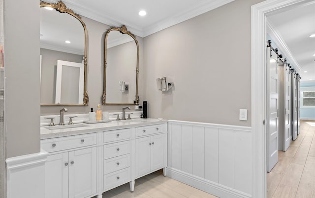 bathroom featuring crown molding, a wainscoted wall, double vanity, recessed lighting, and a sink