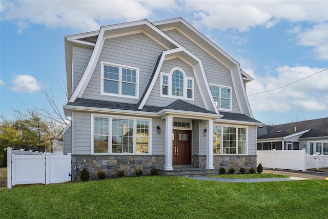 view of front of property featuring stone siding, a front lawn, and fence