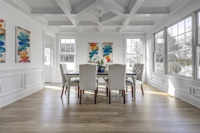 dining room with beam ceiling, a decorative wall, and wood finished floors