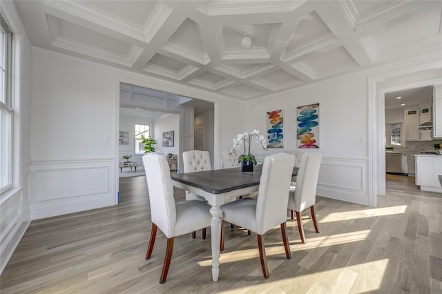 dining room featuring beam ceiling, light wood-style flooring, coffered ceiling, crown molding, and a decorative wall