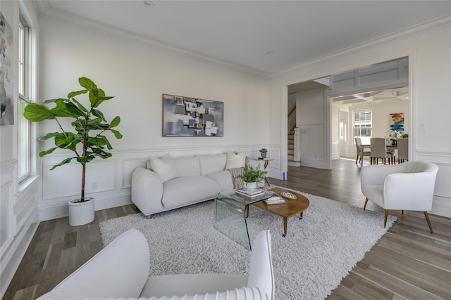 living area featuring a decorative wall, stairs, and ornamental molding