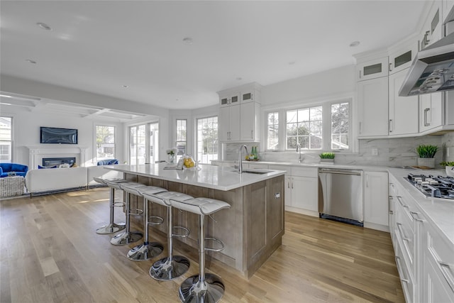 kitchen with light wood-type flooring, a breakfast bar, open floor plan, appliances with stainless steel finishes, and wall chimney range hood