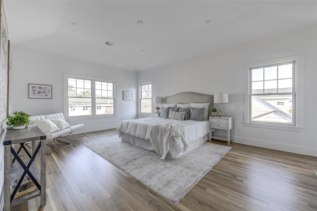 bedroom with visible vents, wood finished floors, and baseboards