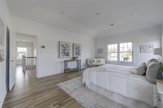 bedroom with visible vents, baseboards, lofted ceiling, and wood finished floors