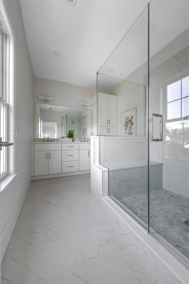 full bathroom featuring a marble finish shower, plenty of natural light, marble finish floor, and a sink