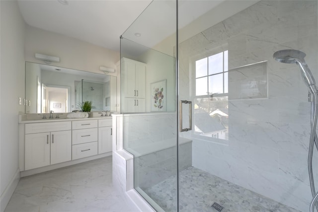 bathroom with a sink, a marble finish shower, marble finish floor, and double vanity