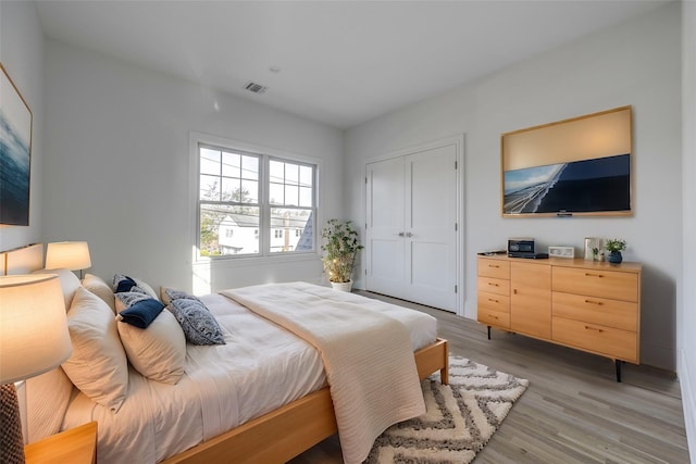 bedroom featuring light wood-style floors, visible vents, and a closet