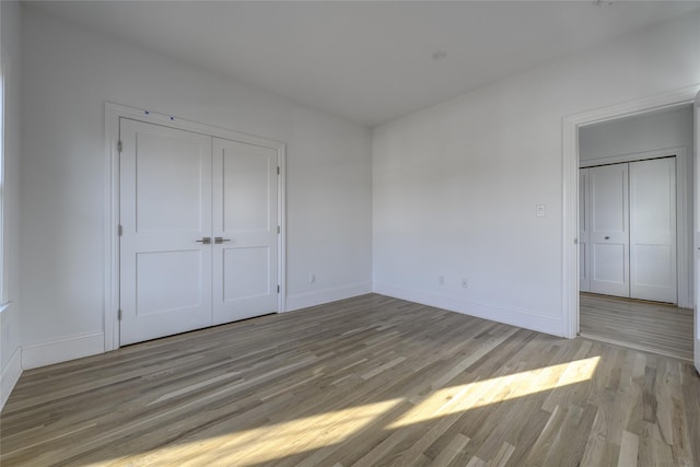 unfurnished bedroom featuring a closet, baseboards, and light wood finished floors