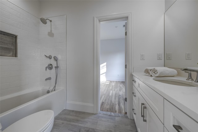 full bath featuring toilet, wood finished floors, vanity, baseboards, and shower / bathtub combination