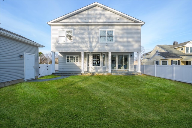 rear view of property with a fenced backyard, a yard, and a gate