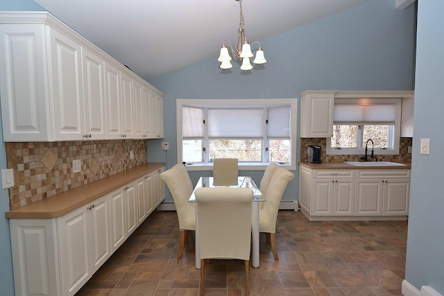 dining space featuring a baseboard radiator, lofted ceiling, a notable chandelier, and stone finish flooring