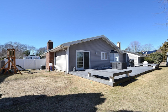 rear view of house featuring a playground, fence, central air condition unit, a chimney, and a yard