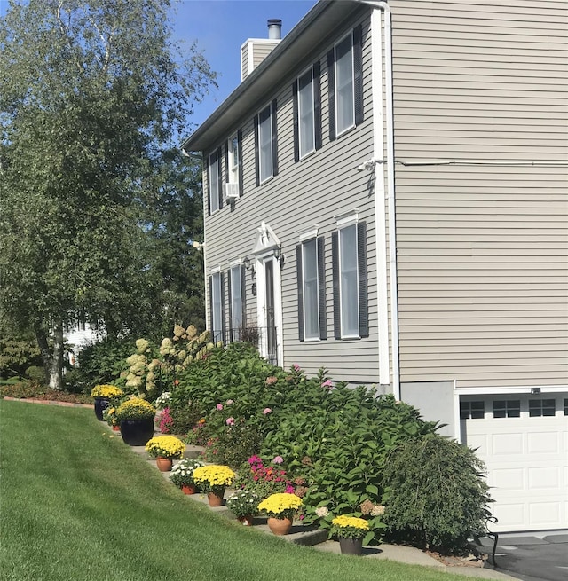 view of side of property with a lawn, a garage, and a chimney