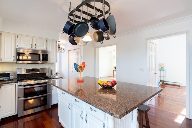 kitchen with backsplash, appliances with stainless steel finishes, crown molding, a toaster, and dark wood-style flooring