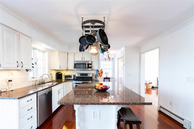 kitchen featuring a breakfast bar, dark wood-style flooring, a sink, stainless steel appliances, and baseboard heating