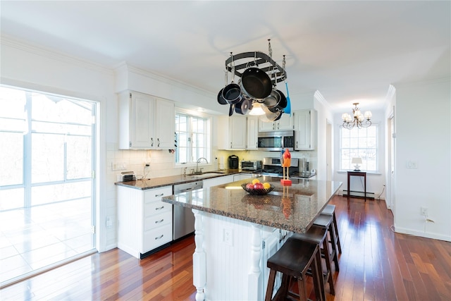 kitchen featuring a sink, ornamental molding, an inviting chandelier, stainless steel appliances, and a baseboard radiator