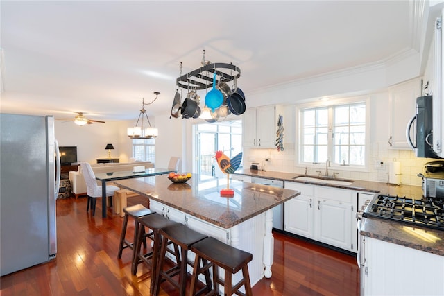 kitchen with dark stone counters, a sink, dark wood-type flooring, appliances with stainless steel finishes, and backsplash