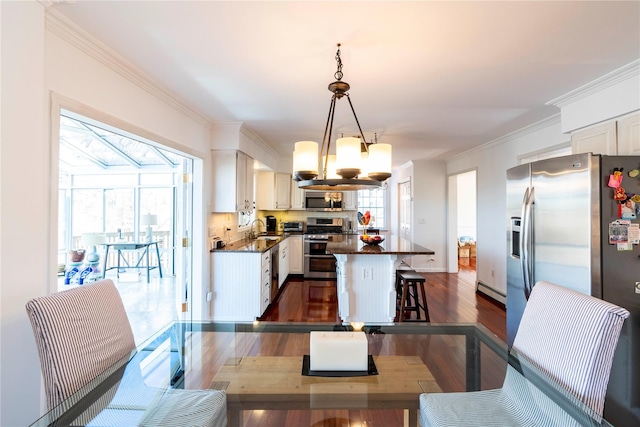 dining space featuring a chandelier, plenty of natural light, dark wood-type flooring, and ornamental molding