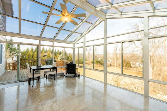 sunroom featuring a wood stove, a skylight, a ceiling fan, and a wealth of natural light