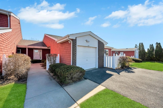 single story home featuring aphalt driveway, a front lawn, brick siding, and a garage