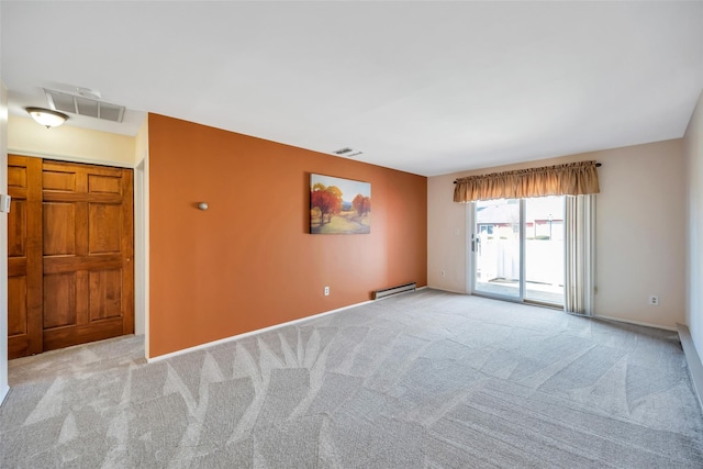 spare room with a baseboard heating unit, carpet, and visible vents