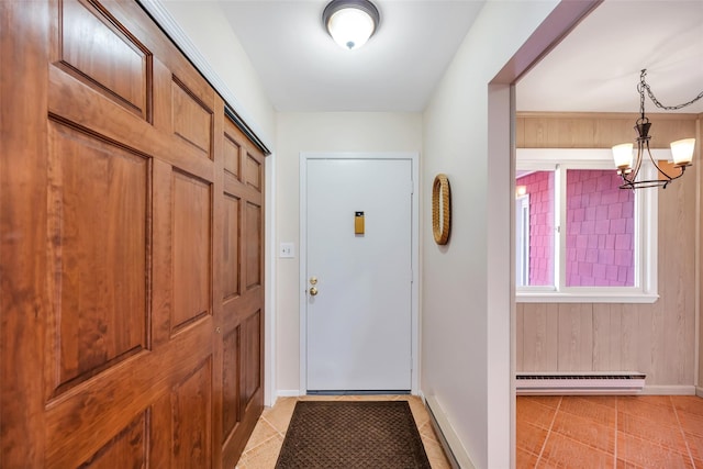 doorway to outside featuring a baseboard heating unit, light tile patterned floors, baseboards, and a chandelier