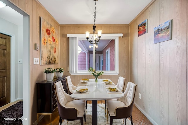 dining space featuring a chandelier, wood walls, and baseboards