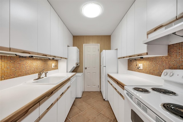 kitchen featuring under cabinet range hood, a sink, white appliances, white cabinets, and decorative backsplash