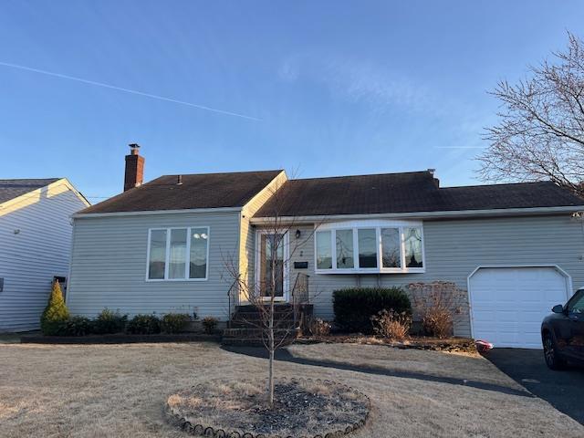 single story home featuring aphalt driveway, a chimney, and a garage