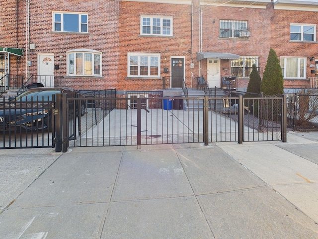 view of front of home with a gate, brick siding, and a fenced front yard