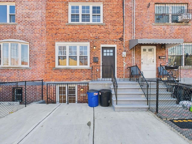 doorway to property featuring fence and brick siding