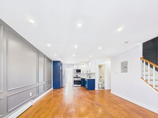 unfurnished living room with stairway, electric panel, a sink, light wood-style floors, and baseboard heating