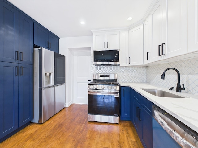 kitchen featuring a sink, blue cabinets, wood finished floors, and stainless steel appliances